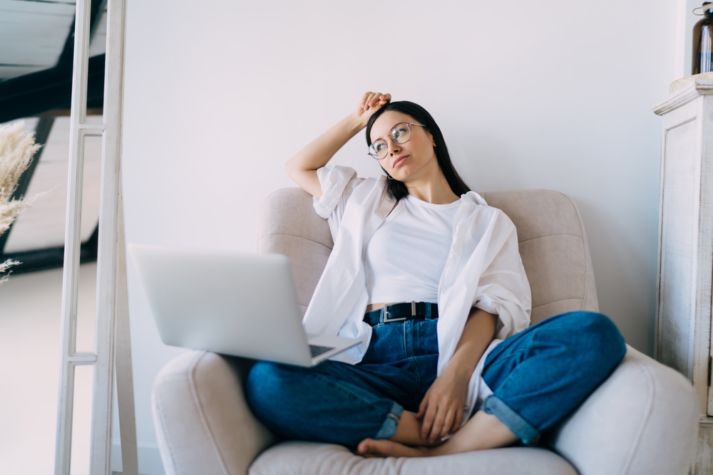 contemplative young woman sitting on her couch